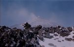 Schneebedecktes vulkanisches Gestein am Ätna mit Wolken im Hintergrund.
